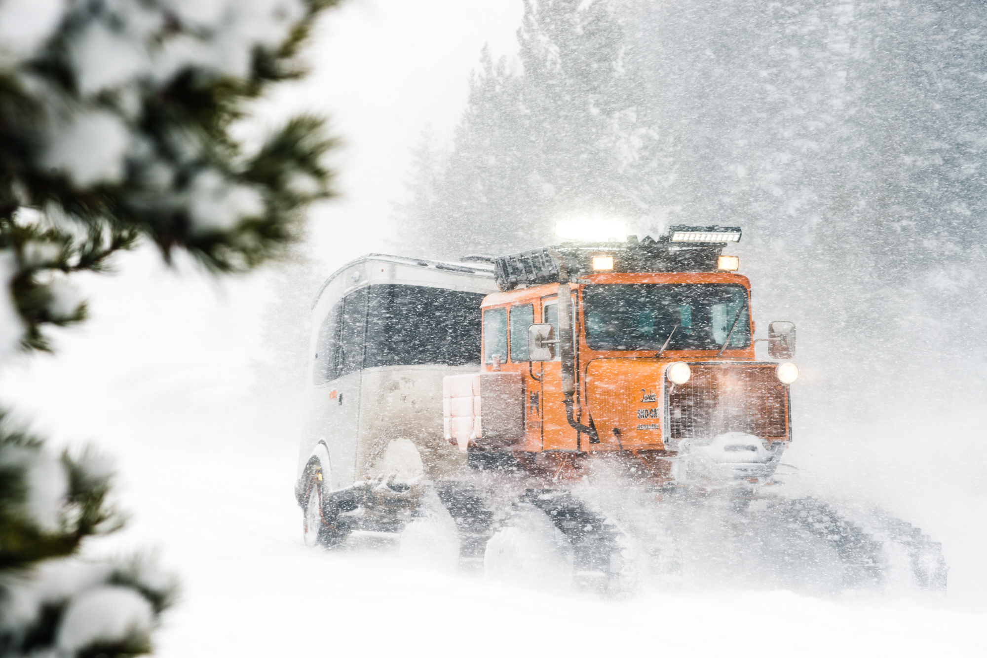 Airstream towed by a vintage Sno-Cat through a snowstorm