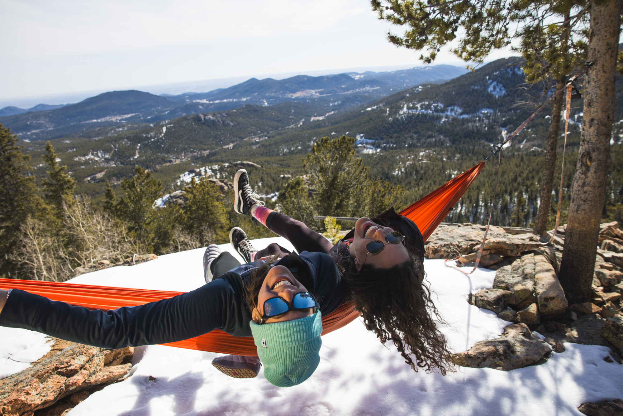Friends laughing in a hammock over a snowy overlook