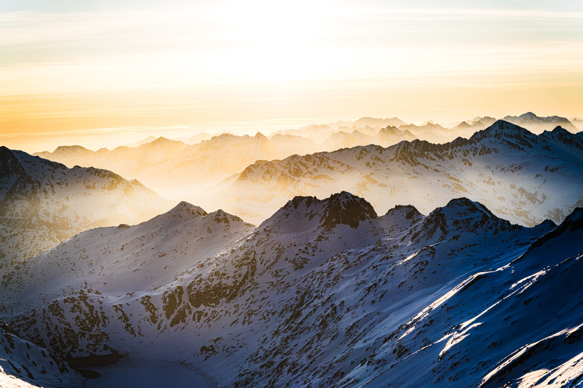 Alpenglow over a snowy backcountry mountain range at sunrise